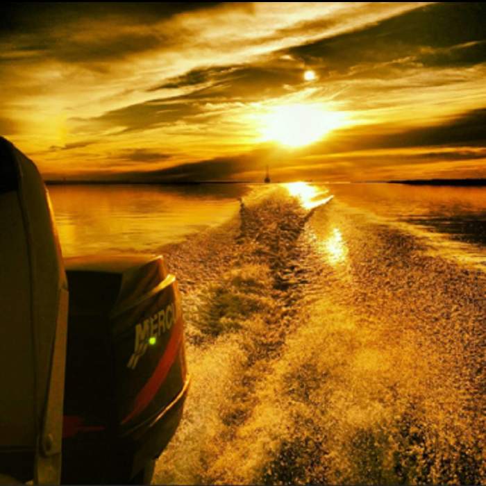 View of sunset on Intracoastal Waterway, Wilmington NC from the back of boat with Mercury motor.