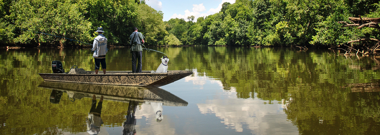 Two guys with a dog fishing in a Lowe jon boat in the Cape Fear River.